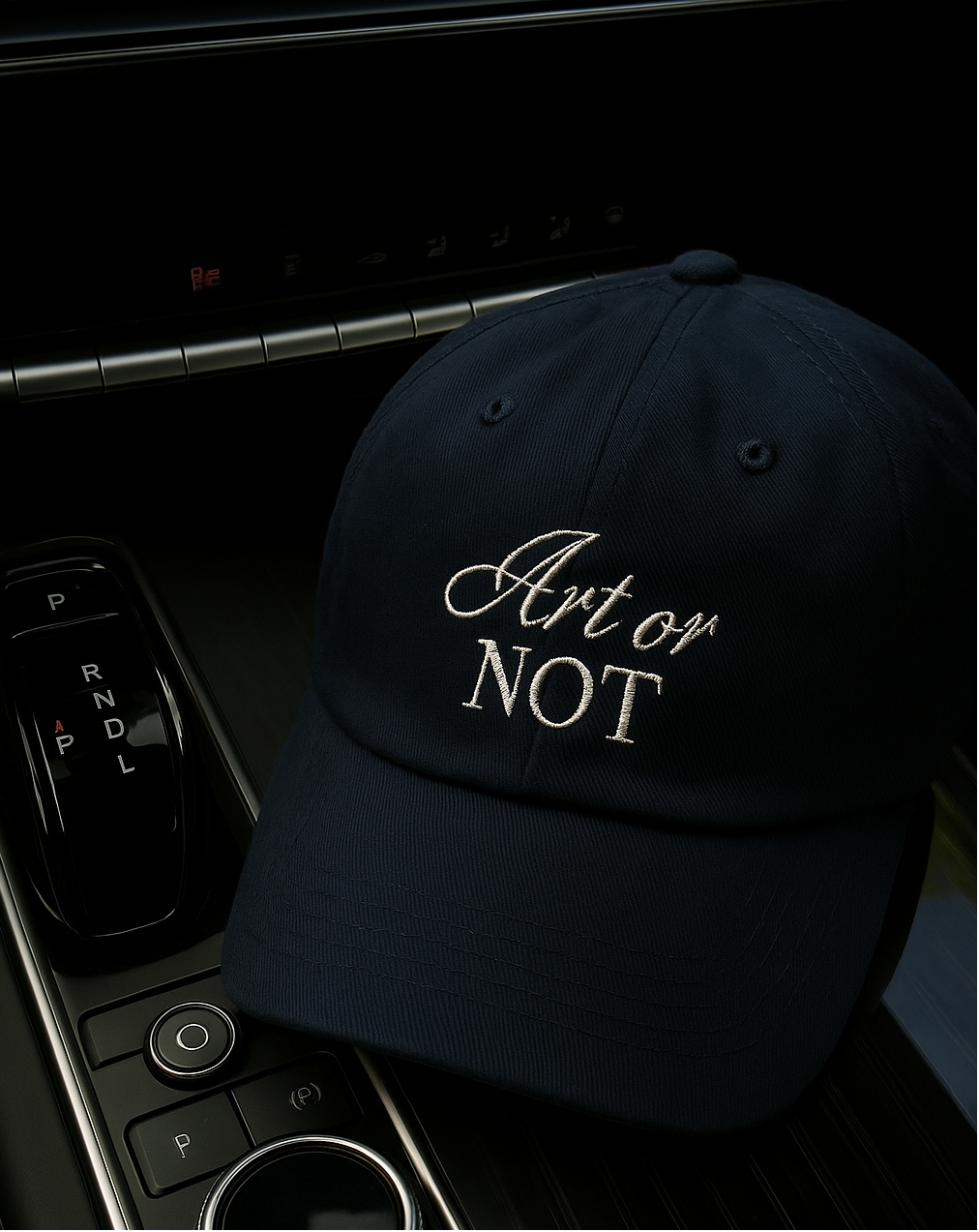Navy embroidered baseball cap for women with “Art or Not” text, photographed inside a car interior